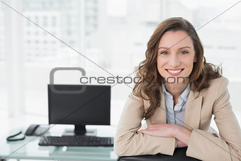 Elegant smiling businesswoman sitting at office desk
