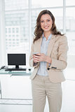 Smiling elegant businesswoman text messaging in office