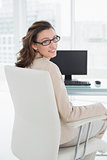 Elegant smiling businesswoman sitting at office desk