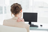 Rear view of businesswoman with neck pain in office