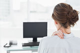 Rear view of a businesswoman with neck pain in office