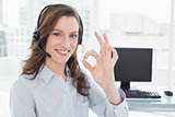 Businesswoman wearing headset while gesturing ok sign in office