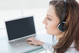 Serious businesswoman wearing headset in front of laptop