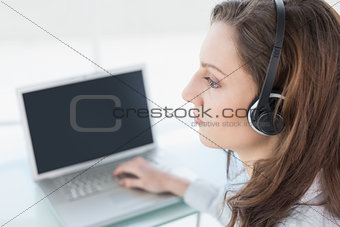 Serious businesswoman wearing headset in front of laptop
