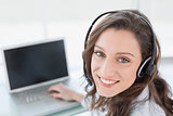 Smiling businesswoman wearing headset in front of laptop