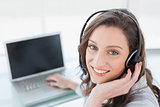 Smiling businesswoman wearing headset in front of laptop