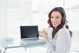 Businesswoman with coffee cup in front of laptop in office