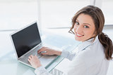 Smiling brown haired businesswoman using laptop in office