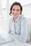 Smiling young businesswoman with laptop in office