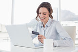 Smiling businesswoman doing online shopping in office