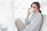 Businesswoman with laptop drinking coffee in office