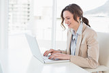 Smiling young businesswoman using laptop in office