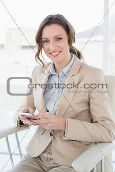 Portrait of an elegant businesswoman text messaging in office