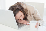 Businesswoman resting head on laptop keyboard