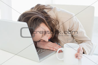 Businesswoman resting head on laptop keyboard