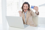 Excited businesswoman doing online shopping in office