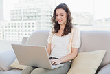Casual young woman using laptop on sofa