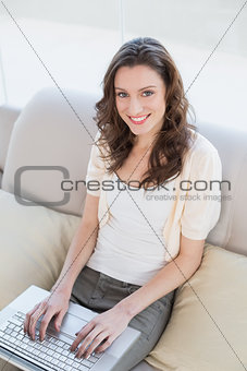 Casual woman using laptop on sofa in a house