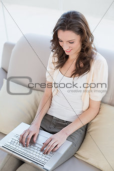 Casual young woman using laptop on sofa