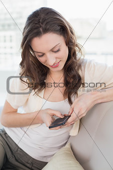 Relaxed young woman text messaging on sofa