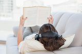 Brown haired woman enjoying music while reading a book