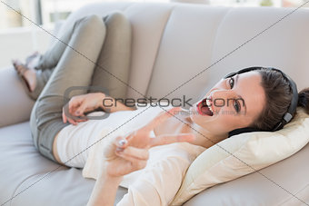 Cheerful casual young woman enjoying music on sofa