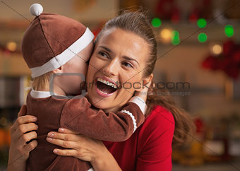 Baby embracing happy mother and in christmas decorated kitchen