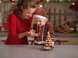Happy mother and baby making christmas tree from cookies