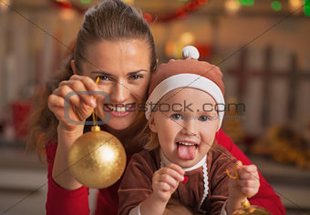 Happy mother and baby showing christmas ball