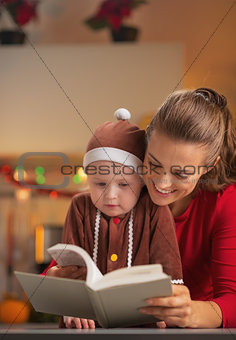Happy mother and baby in christmas costume reading book