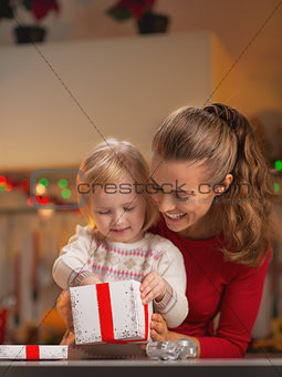 Happy mother and baby opening christmas present box