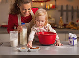 Baby helping mother make christmas cookies in christmas decorate
