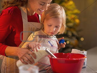 Mother and baby making christmas cookies in kitchen