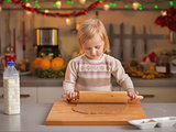 Baby rolling pin dough in christmas decorated kitchen