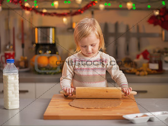 Baby rolling pin dough in christmas decorated kitchen