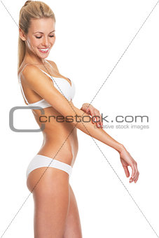Happy young woman in lingerie checking arm skin