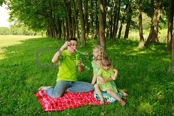 young family blowing bubbles on nature