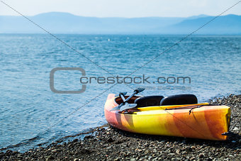 Orange and Yellow Kayak With Oars on the Sea Shore