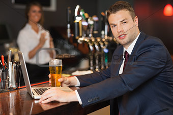 Businessman having a pint while working on his laptop