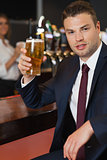 Businessman holding a pint of beer smiling at camera