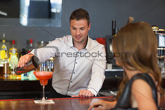 Handsome bartender serving cocktail to gorgeous woman