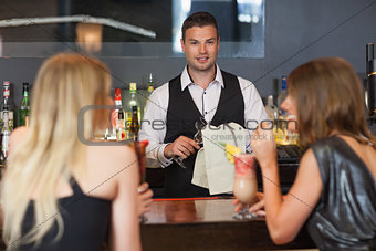 Handsome bartender working while gorgeous women talking