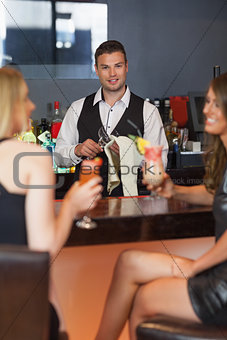 Handsome bartender working while gorgeous friends talking