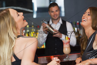 Handsome bartender working while gorgeous friends laughing