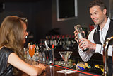 Handsome bartender serving cocktail to beautiful woman