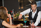 Handsome bartender serving cocktail to attractive woman