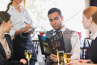 Handsome businessman ordering dinner from waitress