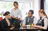 Three business people ordering dinner from waitress