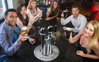Attractive friends raising glasses up smiling at camera