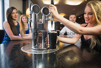 Blonde woman pulling a pint of stout